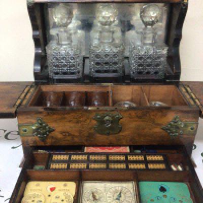A late Victorian burr walnut tantalus with three bottles key and fitted interior brass mounts. The interior with small glasses and games compendium.