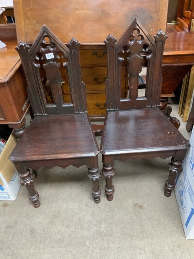 A pair of oak ecclesiastical design hall chairs.