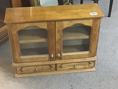 A small stained beechwood cabinet with glass doors above two drawers.