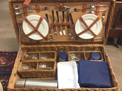 A Picnic set including a flask, glasses , plates, cutlery stored in a wicker basket