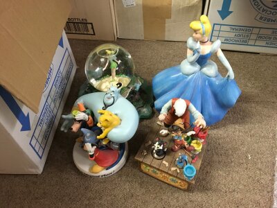 A box containing a collection of Disney figures, plates etc.