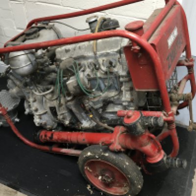 A Vintage Fire Service petrol water pump with detachable hydrant tap and house filters on a red frame. The four cylinder engine with crank start. 