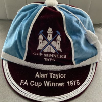 Alan Taylor West Ham FA Cup Final Football Cap: Claret and blue attractive cap with embroidery of the club badge above Cup Winners 1975 wording. Peak has Alan Taylor FA Cup Winner 1975. Certificate from Gentlemen and Players fine traditional caps. Comes in quality box. C/W a few gifts given to Taylor which include 1975 related badges and coasters.