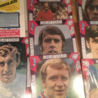 1970 Football Players Original Unused Jigsaw Puzzles: Individual players including Hurst B Charlton George Lee and Webb. Jigsaws are still in cellophane and measure 12 x 17 inches. C/W advertising poster for them. Slight duplication. (11)
