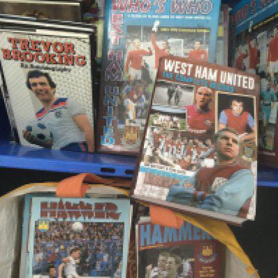 West Ham Football Memorabilia Box: 1981 menu signed by 7 including Ferguson Pearson Brooking and Parkes, 1995 calendar signed by 7, 1981 calendar, undedicated books signed by McAvennie, Hurst and a few dedicated books, Hursts new book unsigned and a large quantity of quite modern programmes, (2 boxes)