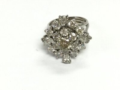 An 18ct white gold (unmarked) diamond cluster ring. Central diamond approx 0.60ct 
Ring size M and 9.23g