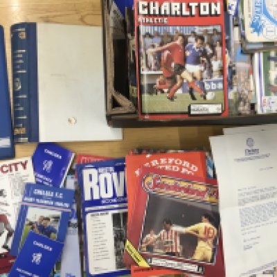 Chelsea Football Memorabilia Boxes: Includes handbooks, Kerry Dixon scrapbook, Fixture cards, Home and away programmes from the 70s and 80s and some supporters club magazines. Instructions to sell. (2 boxes)