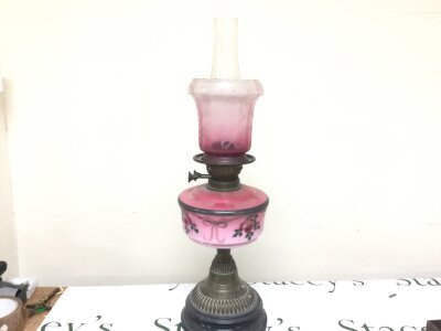 A Victorian oil lamp with cranberry glass shade and pink porcelain reservoir. 59cm tall