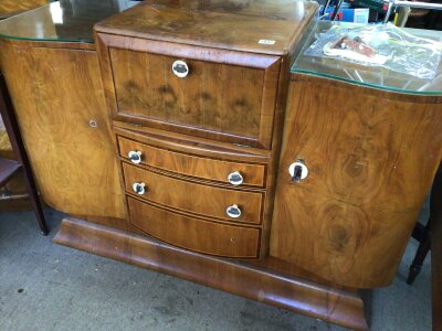 An Art Deco walnut Cocktail cabinet the hinged front and top enclosing a mirrored interior.above three graduating cross banded drawers sold with a bag of loose fittings. Length 138cm