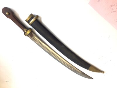 A Russian 1907 pattern Kindjal sword with a a wood grip brass mounts steel blade and leather scabbard marks to the blade.