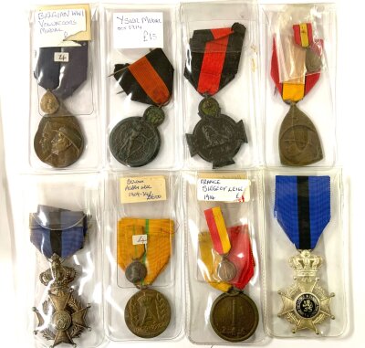 The collection includes various World War I era medals, specifically featuring Belgian Volunteer Medals, the Yser Medal (1914), and a French Siege of Liège (1914) commemorative medal. Other awards shown are the Belgian Commemorative Medal of the 1914-1918 War, the Order of Leopold, and the Croix de Feu.
