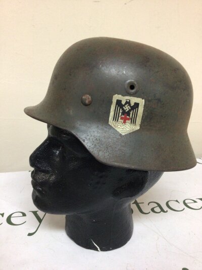 A German Third Reich Military helmet M35 a nice example with green finish showing original patina. The side with a single decal for German Red Cross incorporating Eagle and swastika. The helmet with lining and folded edge and stamped 097. Normally this Decal is used on other models of German Third Reich helmets often Civilian issue.