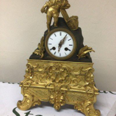 A French late 19th century gilt metal mantel clock the case surmounted with a figure with a basket of grapes the lower section with folate scrolls. Silk suspension movement with pendulum. Height 35cm