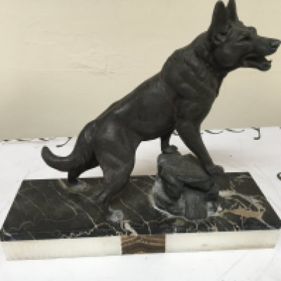 An Art Deco figure of a dog resting on a rock with a multi coloured rectangular marble base. 30cm wide