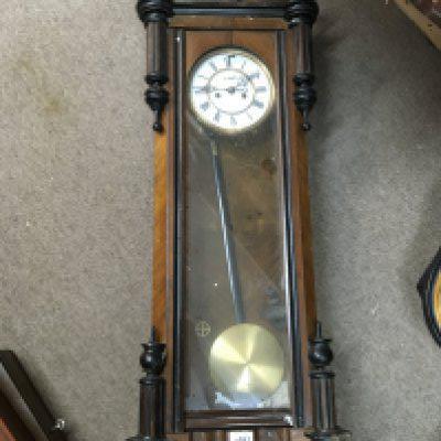 A Walnut Cased Vienna wall clock with a visible pendulum and two weights.