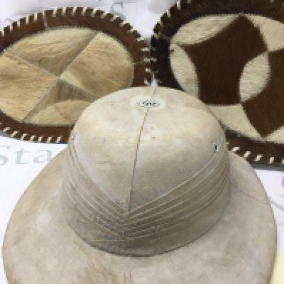 A pith helmet and two oval goat skin mats .