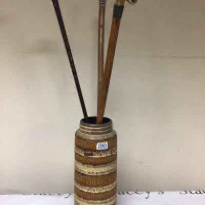 A German Mid 20th century floor vase with three walking sticks one with a silver collar one carved and painted dogs head and an owl (3)