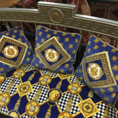 A Versace-style gilt settee upholstered in a blue, gold, and white Lion head-patterned fabric. With three pillows. 88cm tall, 118cm wide , 62cm long