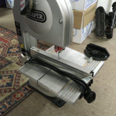 A Draper 190mm two wheel band saw serial number 11030072 with a collection of cased electrical tools including a skillsaw classic.