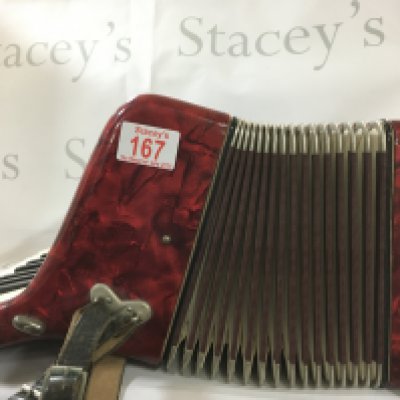 Piano accordion by Worldmaster Foreign. Red, white and gold and is roughly 46 cm wide and 18cm tall.