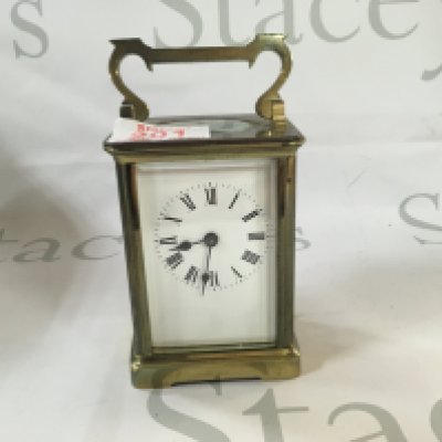 A Victorian antique clock made from brass which has Roman numerals and a visible mechanism.
