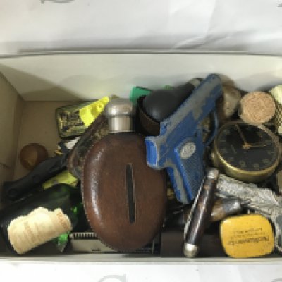 A box containing small and vintage items like clocks, guns, a pocket knife, a small dice and much more.
