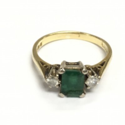 An 18ct gold ring set with central emerald and two diamonds. Size O and 3.59g Postage A