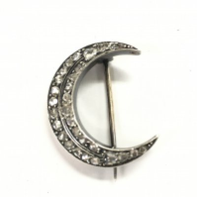 An unmarked silver and gold diamond set crescent brooch.