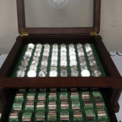 A case containing an extensive collection of never circulated State Quarters in sealed packs of twelve and a state set of 2020 American Quarter dollars all in a well presented cabinet and complete.