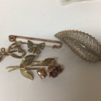 Three small 9carat gold brooches a ribbon tie small butterfly flowers weight 7g and one other brooch marked 935.