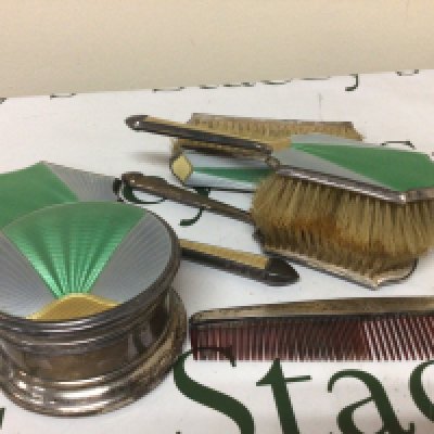 A Silver and enamel Art Deco dressing table set comprising a silver box of circular shape with tricolour enamel mirror sets of brushes and a comb.