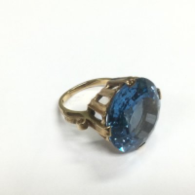 A gold ring set with a large blue stone, approx 113g and approx size N. Shipping category A.
