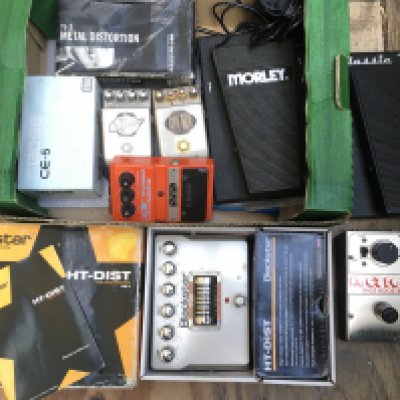 A box of guitar pedals including a a Boss CE-5, Electro Harmonix Hog's Foot bass booster, Blackstar HT-DIST and others.