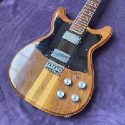 A late 1970's Gretsch Committee Solid Body Guitar in walnut and maple with walnut and maple hippie sandwich type neck and smoked plexiglass control cavity cover. All original with light playwear, frets fine and look original with evidence of slight fret stone job and a few small chips to the body edge consistent with age and use. No case.