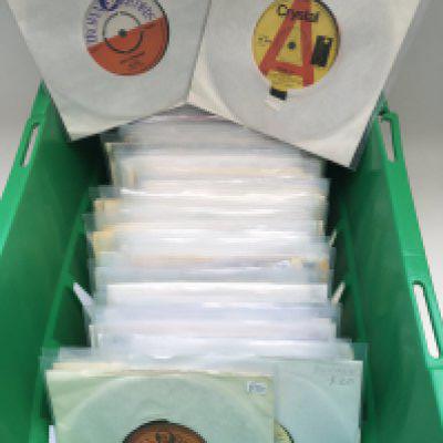 A box containing a collection of reggae 7" singles by various artists including Bob Marley, Steel Pulse, Melodians, Desmond Dekker and many more.