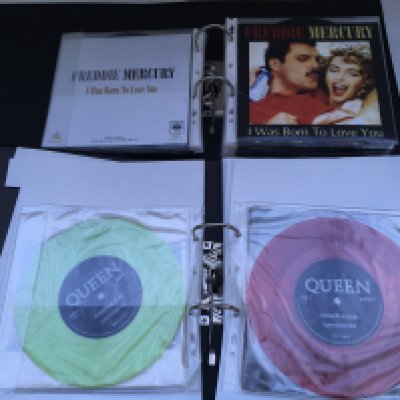 A box containing four binders of Queen and related 7" singles including fanclub exclusive editions and coloured vinyl.