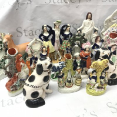 A large collection of Staffordshire figures including Courting couple, dog, cream cow, clock figure groups without clock movements. This lot cannot be posted