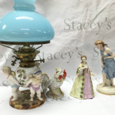 Porcelain figures including Worcester against the wind , Madame du Barry (with restoration) Mesissen cherub figure group oil lamp with a light blue glass shade, German rooster figure. This lot cannot be posted