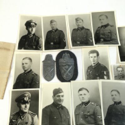 An assortment of German photos , German armband , Navrik arm shield, Demansk arm shield and a gas mask container .Postage cat a