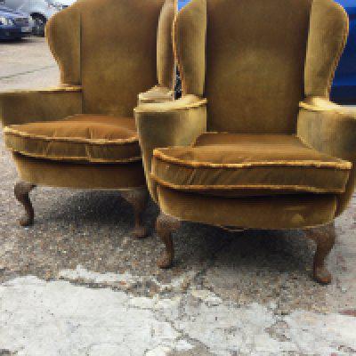 A pair of wing back open armchairs with carved cabriole legs .