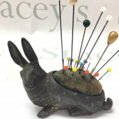 A small Victorian figure of a hare as a hat pin stand 8cm tall, 11Cm wide.