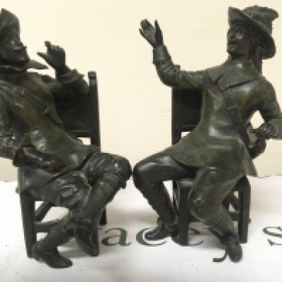 A pair of bronzed metal figures of seated cavaliers the chair rail stamped Geo Maxim (2) Height 26cm one leg damaged.