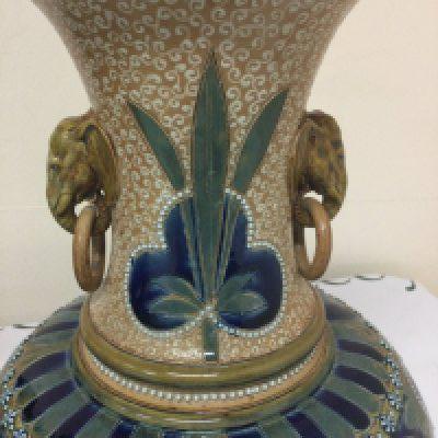 A unusual Florence Barlow Doulton Lambeth stoneware Art pottery vase decorated with stylistic Flowers and foliage with elephant ring handles in a blue green brown glaze . 32 cm. Three beads missing.