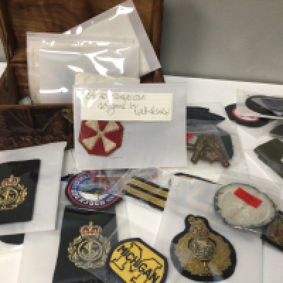 A small carved camphor wood trunk containing a quantity of cloth military badges including American badges