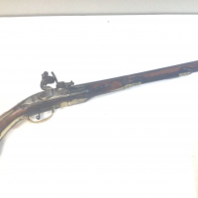 An 18th Century Italian flint lock pistol with a full length carved walnut stock with brass fittings and steel action