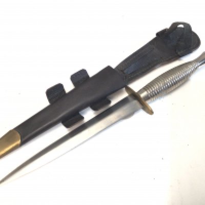 A Fairbrain Sykes Commando Knife Chrome finish made in Sheffield type 3. The brass cross guard with makers Stamp. leather scabbard..