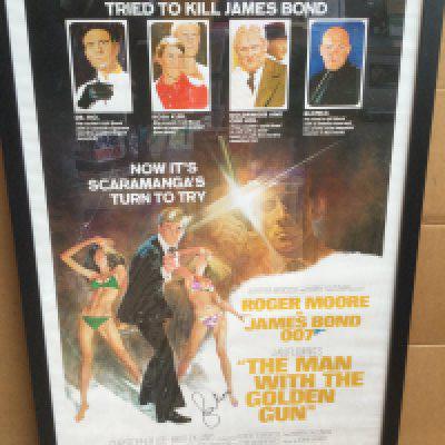 A framed and glazed James Bond film poster for 'The Man With The Golden Gun' signed by Sir Roger Moore with COA. Approx 66cm x 96cm including frame.