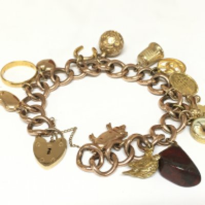 A 9ct gold charm bracelet with multiple charms including a 22ct gold band. Approximately 42g