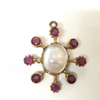 An unmarked yellow metal moonstone and ruby star brooch. 3.65g