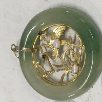 A jade pendant the centre with a design of a stork with gem stone inset .